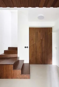 A modern staircase entryway with wooden paneling, featuring white walls and a ceiling.
