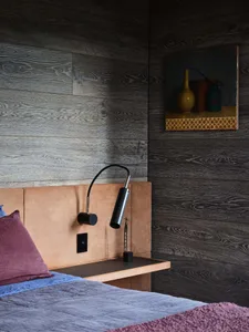Bedroom with industrial design featuring a wood-paneled wall and minimalist bed setup