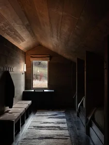 Modern minimalist bedroom with wood paneling, a window with natural light, and a cozy sitting area.