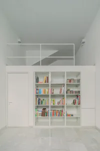 A minimalist bookstore with concrete shelves filled with books and DVDs.