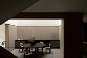 Modern minimalist dining room featuring wooden furniture and a round table with chairs.