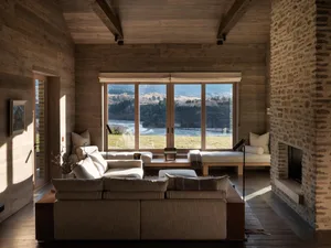 A modern minimalist living room with large windows showcasing a scenic landscape, featuring a wooden interior design with a s