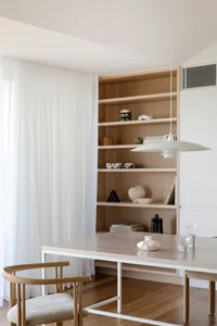 Modern minimalist dining room with wooden furniture, white sheer curtains, and a minimalist pendant light.