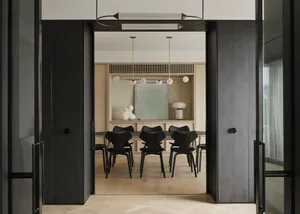 A modern minimalist residential interior with a wooden table, metal chairs, and a glass lamp.