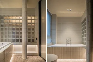 Modern bathroom with white ceramic tiles, glass block wall, and freestanding bathtub.
