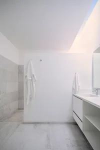 A modern bathroom with white walls and marble flooring and walls