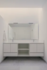 Modern minimalist bathroom with white walls, sink, and cabinets.