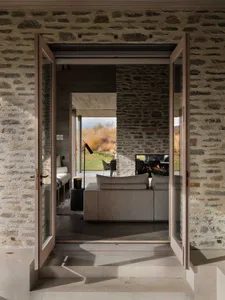 A contemporary living room with stone walls and concrete floors.