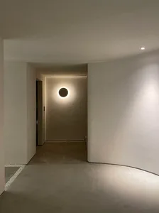 Modern hallway with minimalist design featuring a circular light fixture and concrete floor.
