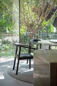 Modern home office interior with wooden furniture and large windows showcasing greenery outside.