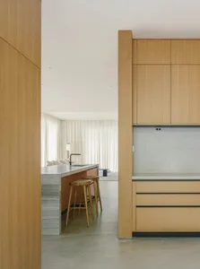 A modern kitchen interior with wooden cabinets and a marble countertop.
