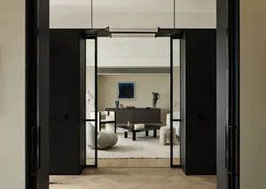 Modern living room with black frame door, white and dark wood furniture, and minimalist decor.