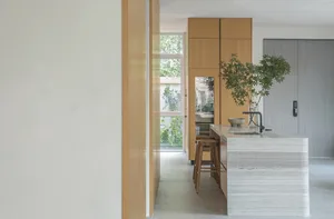 A modern kitchen with white marble countertops and wooden cabinets.