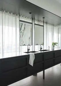 Modern, minimalist bathroom featuring a marble countertop with black fixtures.
