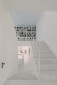 Modern minimalist interior with white marble staircase and glass walls.