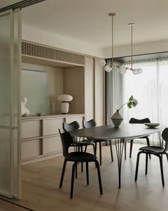A modern residential dining room featuring a sleek table, black chairs, and a minimalist decor.