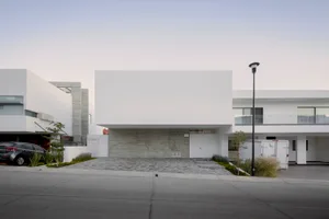 Modern, minimalist, residential exterior with concrete facade and white walls.