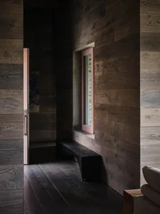 A modern residential interior with wooden walls and a window allowing natural light to enter.
