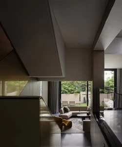 A modern residential space with glass and steel materials, featuring a comfortable seating area and an open concept design.