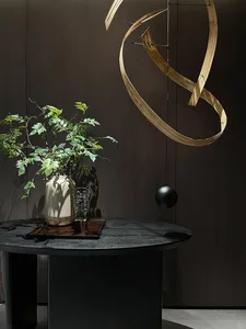 A modern interior design with a wooden decorative object and a round, dark table with green plant.