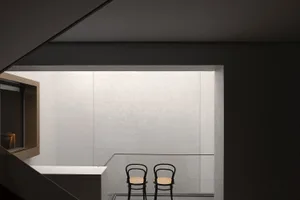 Two minimalist chairs in a modern, minimalist concrete interior space.