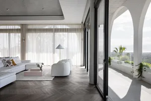 A modern living room with white furniture and large windows showcasing a terrace.