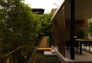 A minimalist patio area with stone walls and a modern table setting.