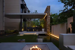A modern contemporary garden featuring concrete elements and warm lighting during the evening.