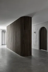 A sleek, modern minimalist interior featuring dark wood and concrete materials.