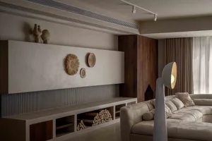 Modern living room with concrete walls, wooden furniture, and textured decorative elements.
