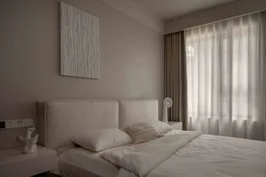 Modern minimalist bedroom with a fabric headboard and white bedding.