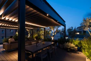 A modern, minimalist rooftop patio with concrete flooring, metal furniture, and LED lighting features.