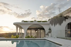 A modern residential architecture with a concrete pool and ocean view.