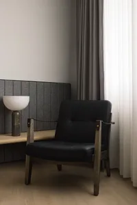 A modern, industrial-style furniture piece featuring a black leather seat and backrest with wooden legs, set against a minima