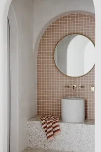A minimalist bathroom with a terrazzo countertop, sink, and mirror.