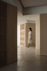 A minimalist interior space with wooden walls and a person walking through it.