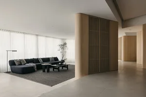 Modern minimalist living room with a black sectional sofa, wooden paneling, and a large floor lamp. Floor-to-ceiling windows 
