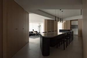 A modern, minimalist residential kitchen with a black island and wooden cabinetry.