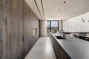 A modern kitchen with concrete countertops and dark wood cabinets.