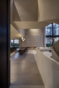 A modern living room with concrete flooring, minimalist furniture, and a fireplace.
