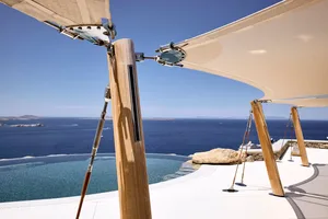 Modern outdoor space with covered seating area and infinity pool overlooking the sea.