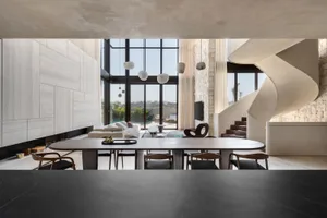 Modern living room with concrete walls, glass windows, and metal furniture.