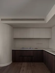 Modern kitchen featuring white cabinets and wooden flooring with a stainless steel stove and white countertops.