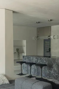 A modern living room with a marble counter and sleek, black stools.