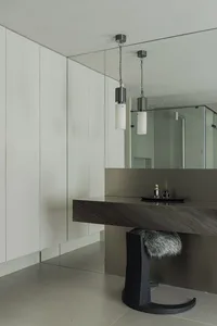 Modern minimalist bathroom featuring a sleek, concrete vanity with a glass shower enclosure, geometric shapes, and a fur stoo