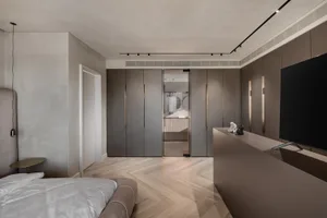 A modern minimalist bedroom with a large bed, wooden flooring, and metallic accents.