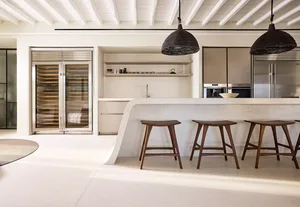 Modern minimalist kitchen featuring terrazzo countertops and wooden bar stools.