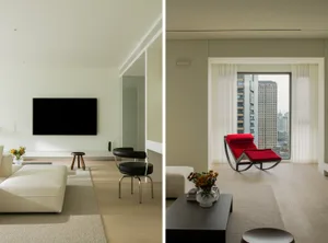 Modern minimalist living room with white furniture, red accent chair, and city view.
