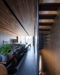 Modern, minimalist living room with wooden flooring and concrete walls.