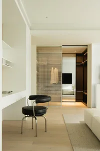 Modern minimalist office space with white furniture and open closet.